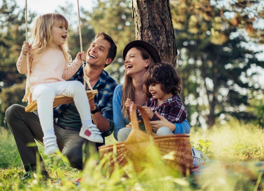 Young,Caucasian,Family,Playing,On,A,Swing,While,On,A